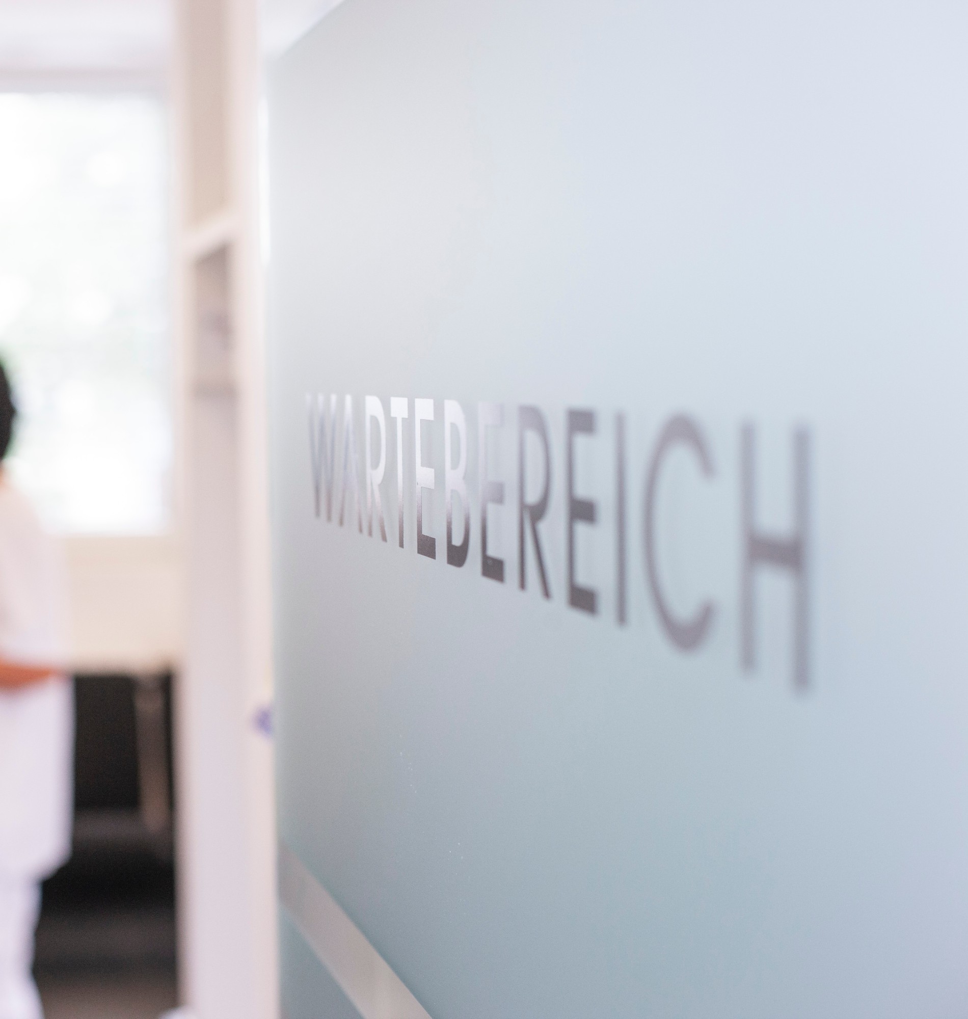 Milchglasscheibe mit Aufschrift Wartebereich in einer Praxis